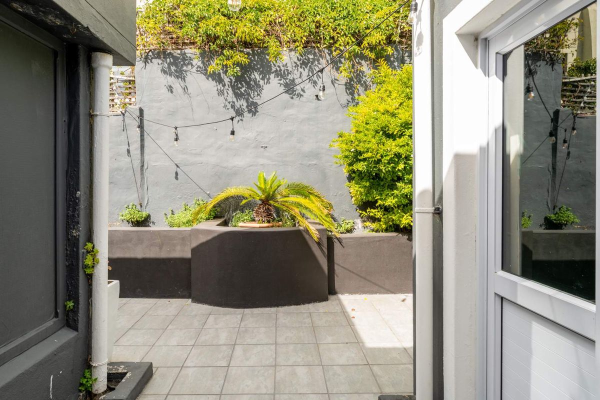 A private, paved rear courtyard featuring built-in planter boxes and a rendered boundary wall, providing a low-maintenance outdoor space.