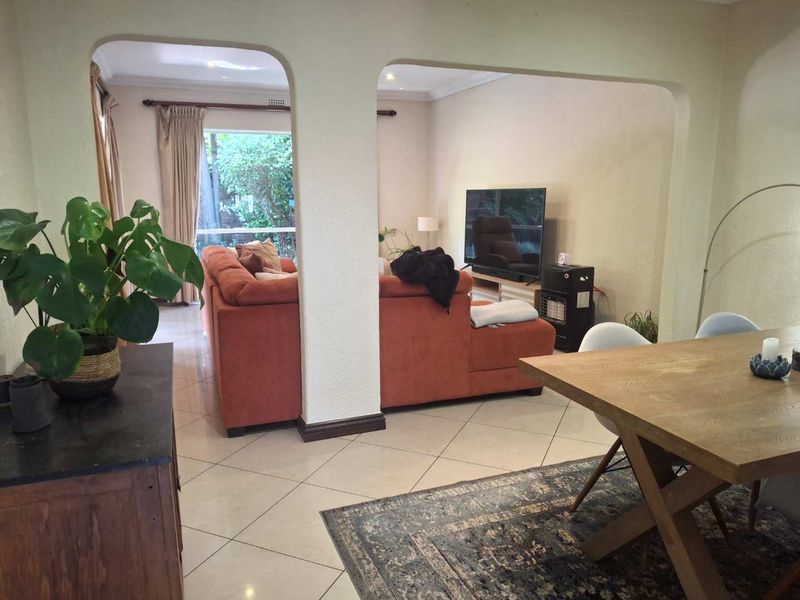 Open-plan living and dining area featuring tiled flooring, arched transitions, and recessed lighting, creating a connected and functional space for daily living.