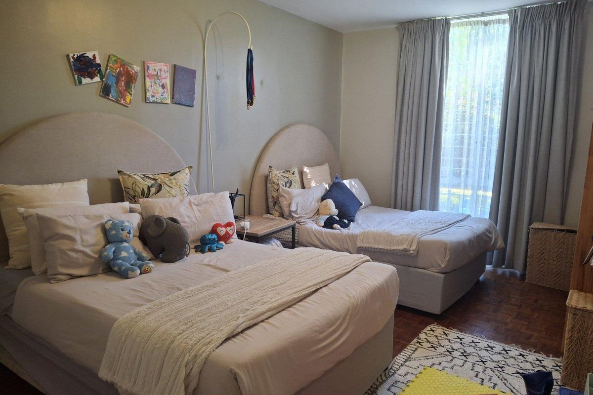 A spacious bedroom featuring parquet flooring and large windows with floor-to-ceiling curtains, offering a comfortable and well-lit living space.