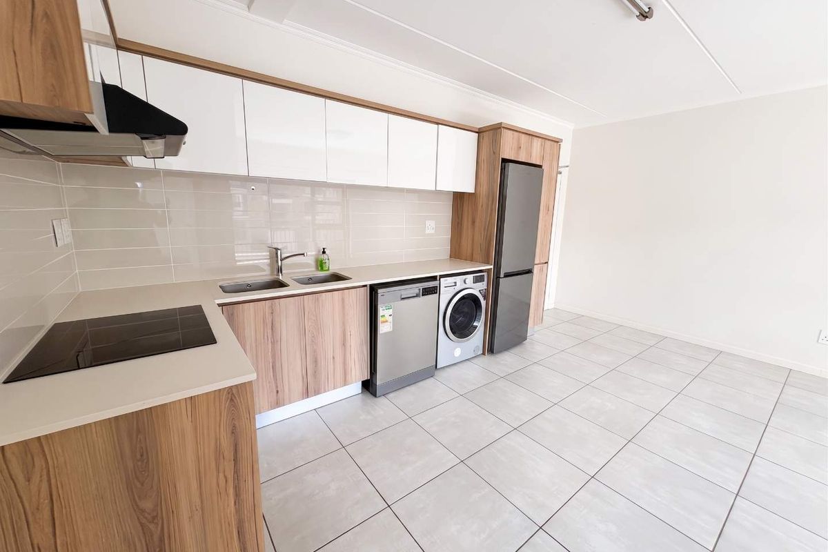 Modern kitchen featuring light wood-grain cabinetry, stone countertops, integrated hob, extractor fan, and tiled flooring in a clean, open-plan layout.