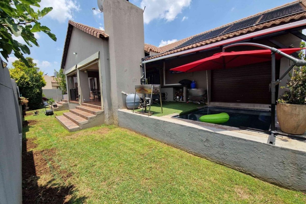 Rear exterior view featuring a raised patio area, a small swimming pool, and a landscaped garden with a tiled staircase.