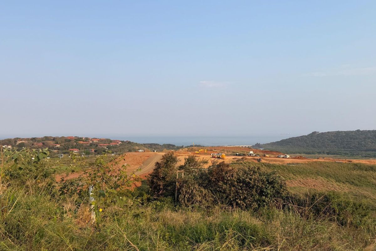 An elevated view of a large, undeveloped residential land plot featuring coastal landscape and distant ocean views.