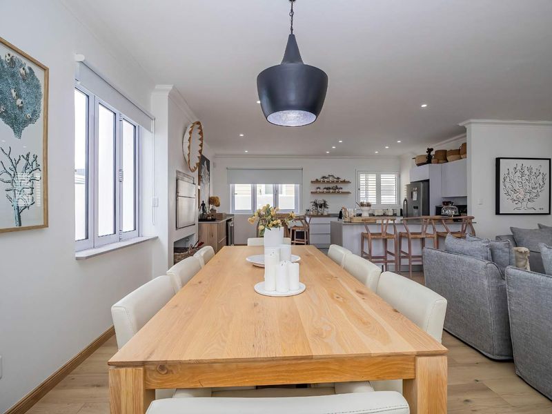 A bright and modern open-plan living and dining area featuring timber flooring, recessed lighting, and a well-appointed kitchen with a central island.