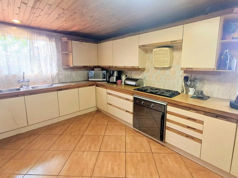 A functional kitchen featuring built-in cabinetry, laminate countertops, a gas hob, built-in oven, and a distinctive timber-clad ceiling.