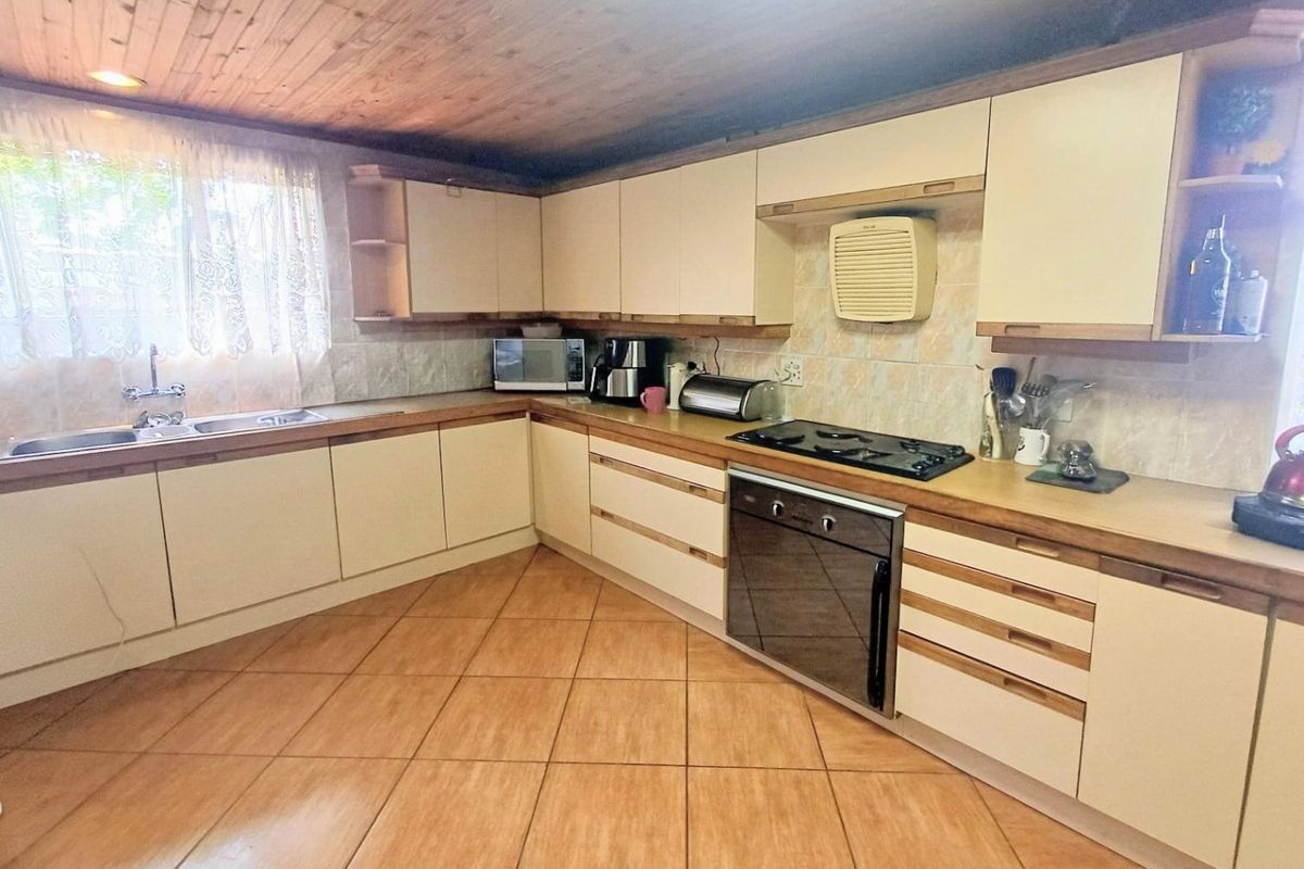 A functional kitchen featuring built-in cabinetry, laminate countertops, a gas hob, built-in oven, and a distinctive timber-clad ceiling.
