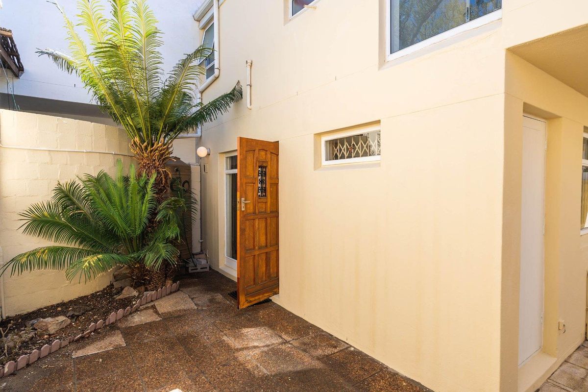 A private rear courtyard area featuring paved flooring, a timber entrance door, and security window grilles.