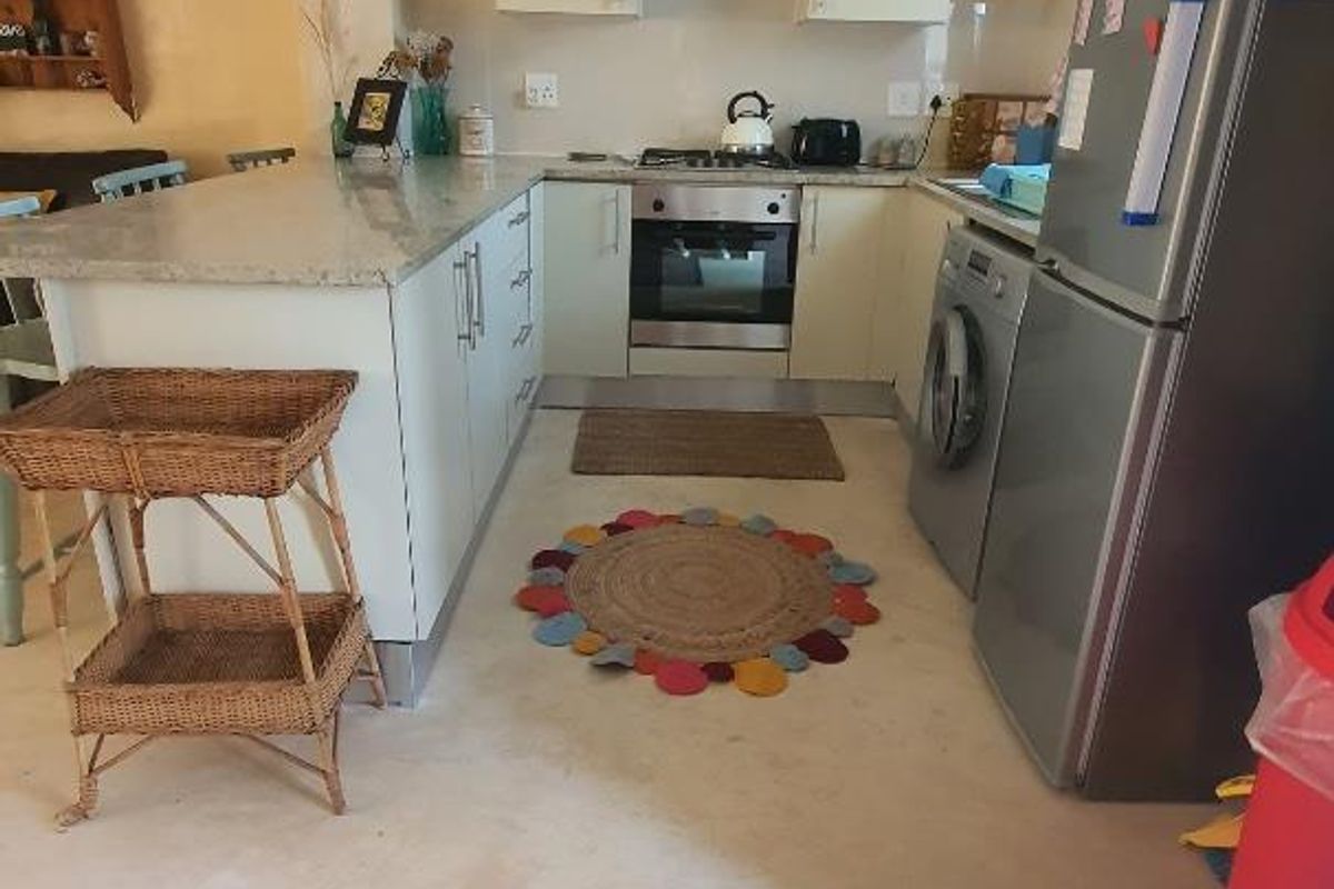 A functional kitchen featuring built-in cabinetry, stone countertops, a gas hob, and an integrated laundry area, offering a practical layout for daily use.