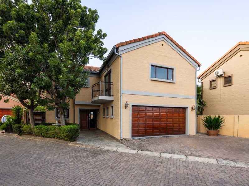 Front elevation of a two-story residential house featuring a paved driveway, integrated garage, and a small balcony with metal railing.
