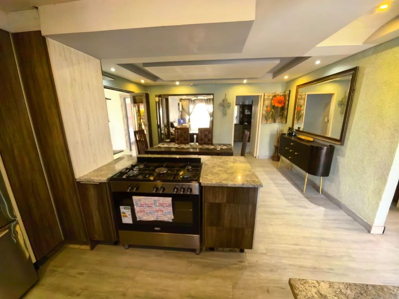 Open-plan kitchen and dining area featuring modern cabinetry, stone countertops, a gas stove, and recessed ceiling lighting with a seamless flow.