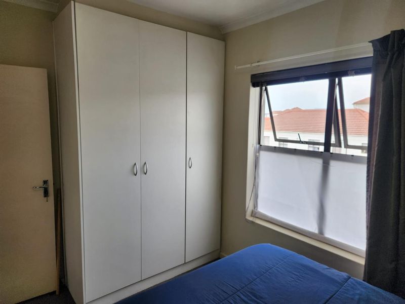 A bedroom featuring a large white built-in wardrobe and a casement window providing natural light.