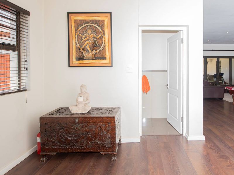 A well-maintained hallway featuring dark laminate flooring, neutral walls, and access to an adjoining room.