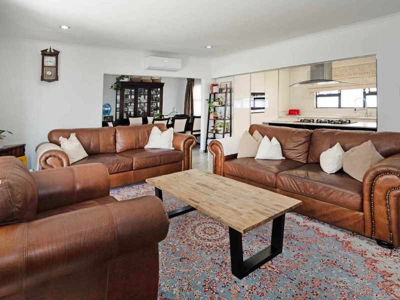 Spacious open-plan living area featuring a modern kitchen with integrated appliances, recessed lighting, and a split-system air conditioner for climate control.