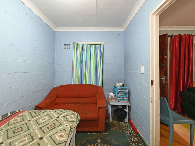 A bedroom featuring exposed blockwork walls and cove cornicing, requiring cosmetic updates to improve the overall aesthetic and finish.