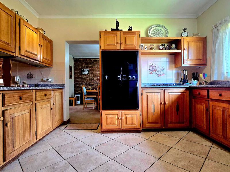 Traditional kitchen featuring warm wooden cabinetry, granite countertops, built-in oven, and gas hob, with direct access to the adjacent dining area.