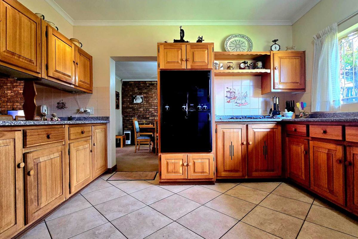 Traditional kitchen featuring warm wooden cabinetry, granite countertops, built-in oven, and gas hob, with direct access to the adjacent dining area.
