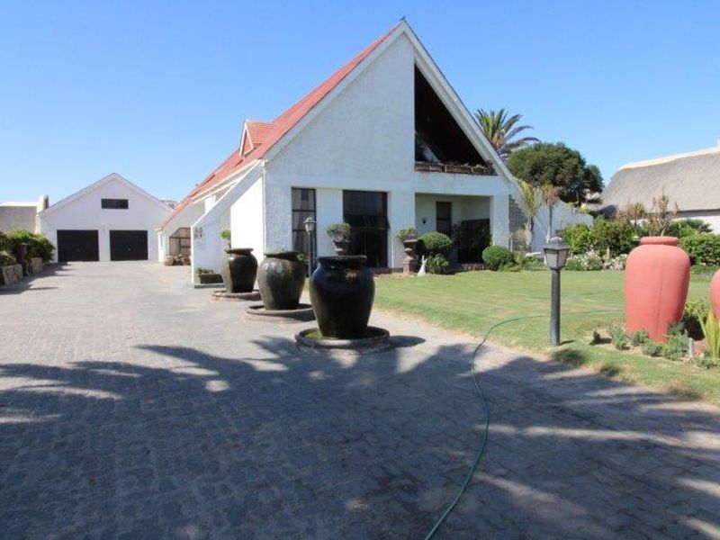 Front view of the property featuring a paved driveway, double garage, and a well-maintained garden area with a pitched roof architectural style.
