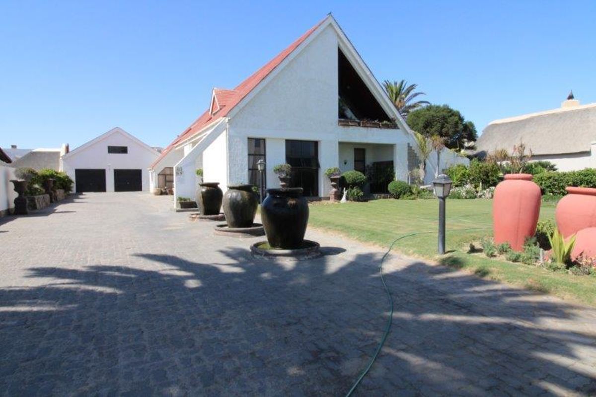 Front view of the property featuring a paved driveway, double garage, and a well-maintained garden area with a pitched roof architectural style.