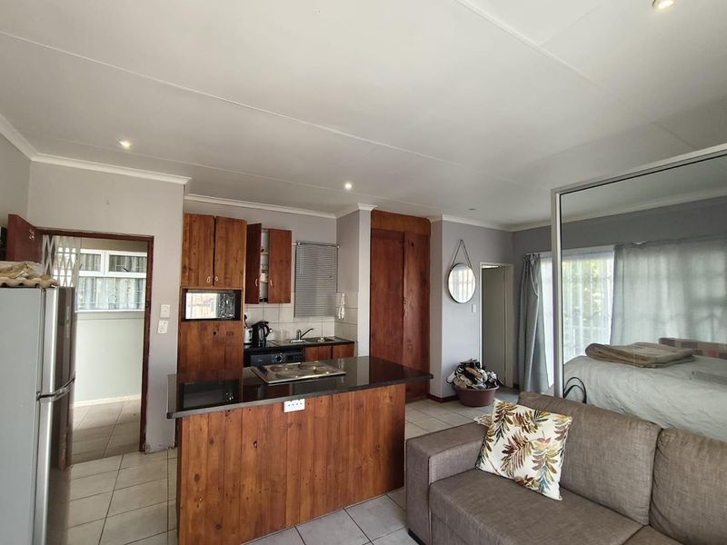 Open plan living area featuring a kitchen with wooden cabinetry, granite countertops, and a built-in hob, seamlessly connected to the living and bedroom space.
