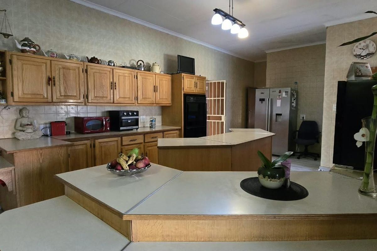 Spacious kitchen featuring extensive wooden cabinetry, tiled wall finishes, and a large multi-level breakfast bar island with integrated oven.