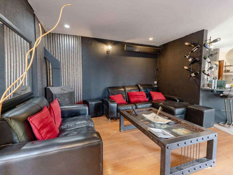 A living room featuring dark walls, laminate flooring, a wood-burning fireplace, and a wall-mounted air conditioning unit.