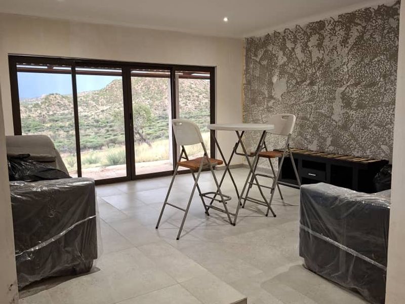 A living area featuring tiled floors, recessed lighting, and large sliding glass doors with scenic views, complemented by a textured feature wall.