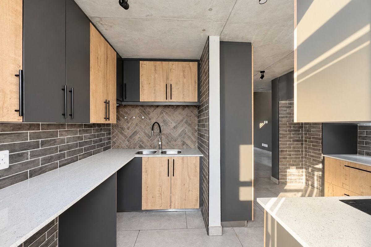 Modern kitchen featuring two-tone cabinetry, stone countertops, herringbone tile backsplash, and exposed concrete ceilings in an open-plan layout.