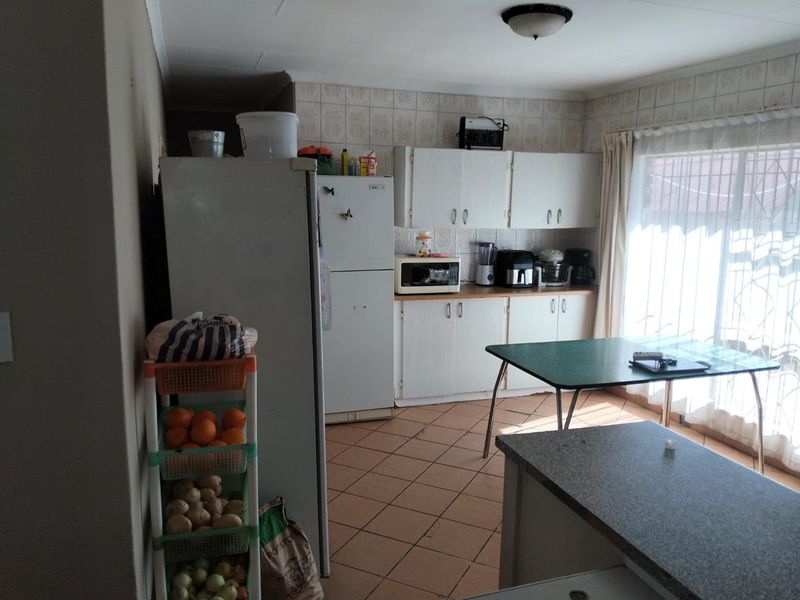 A functional kitchen featuring dated cabinetry, tiled backsplash, and tiled flooring, offering potential for a modern renovation to enhance the space.