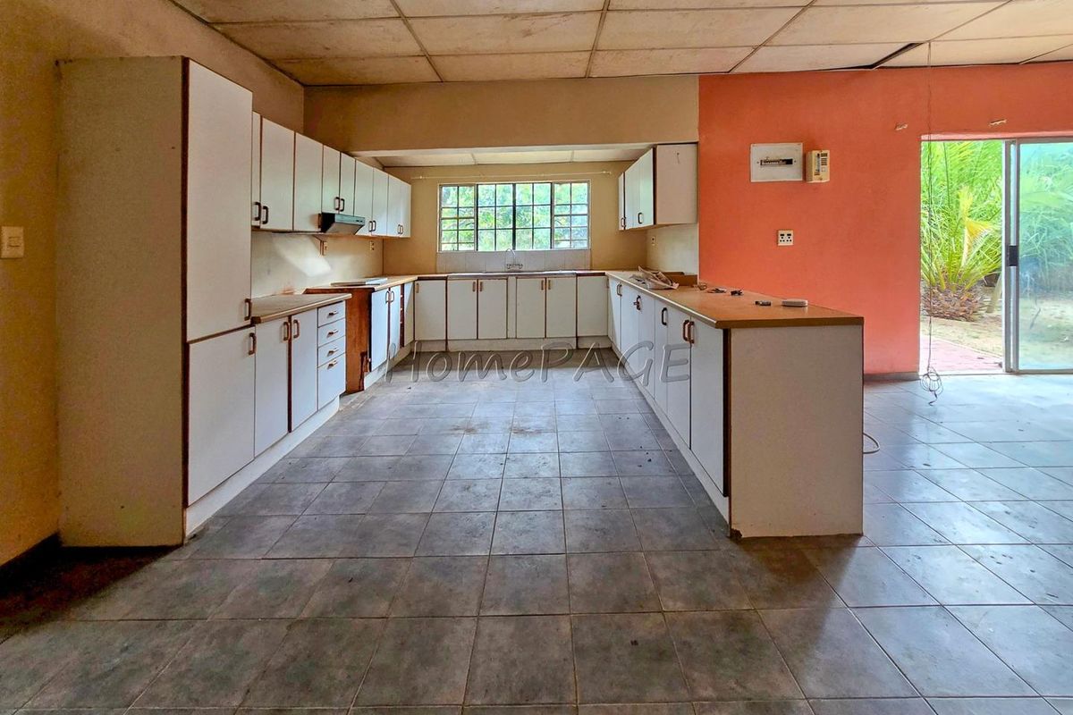Spacious kitchen featuring U-shaped cabinetry, tiled flooring, and direct access to the outdoor area through sliding glass doors.
