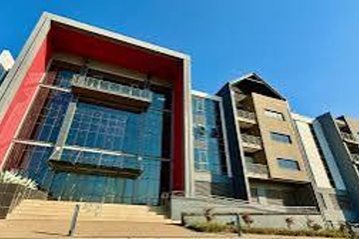 Modern multi-story office building featuring a striking glass facade, red architectural accents, and integrated balconies with steel railings.