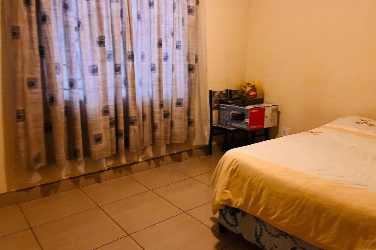 A bedroom featuring tiled flooring and a window with curtains.