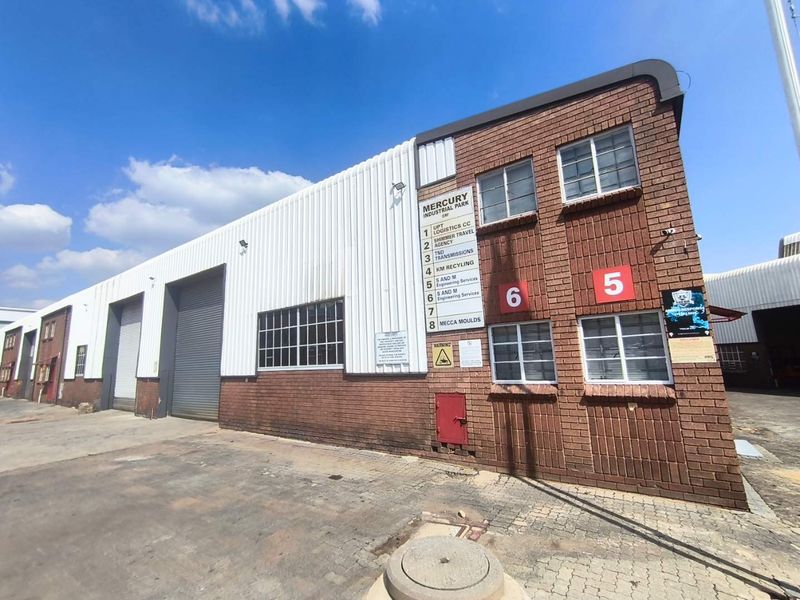 Exterior view of an industrial warehouse unit in Mercury Industrial Park, featuring brick and metal cladding, roller shutter doors, and clear unit signage.