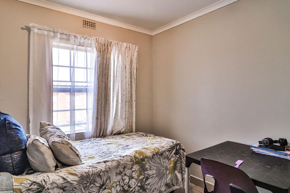 A functional bedroom featuring a window with natural light, neutral wall finishes, and standard ceiling coving.