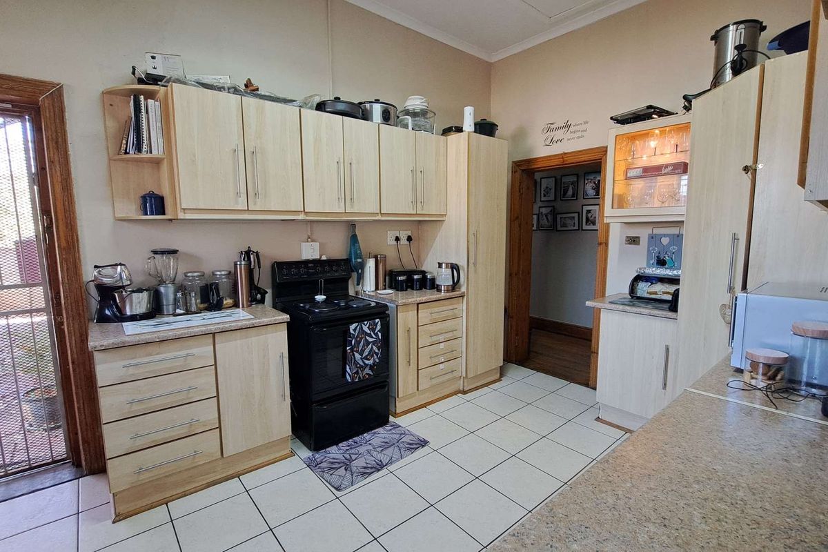 Functional kitchen featuring light wood-tone cabinetry, laminate countertops, a freestanding stove, and tiled flooring with direct access to an outdoor area.