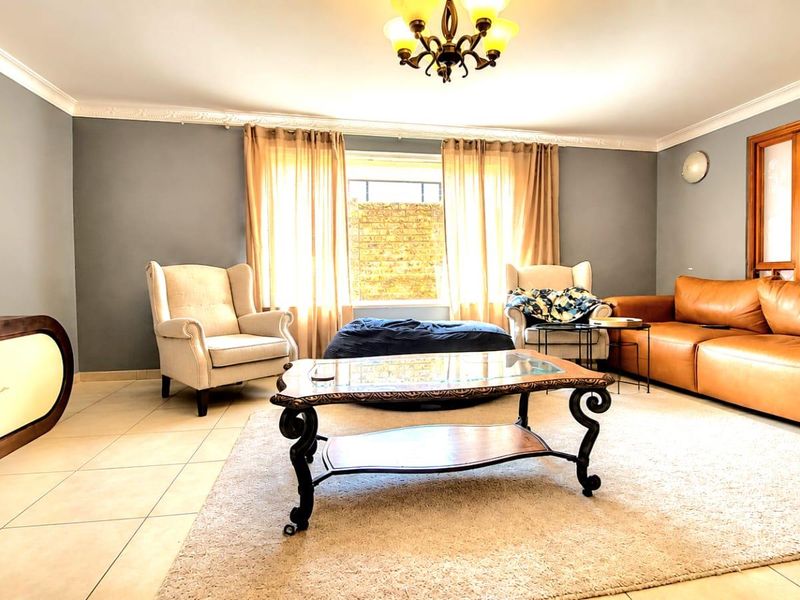 A spacious living room featuring tiled flooring, crown molding, and neutral wall tones, providing a comfortable and well-lit area for relaxation.