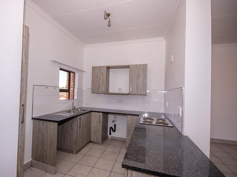 A clean, functional kitchen featuring modern laminate cabinetry, granite countertops, an electric hob, and tiled finishes, ready for immediate use.