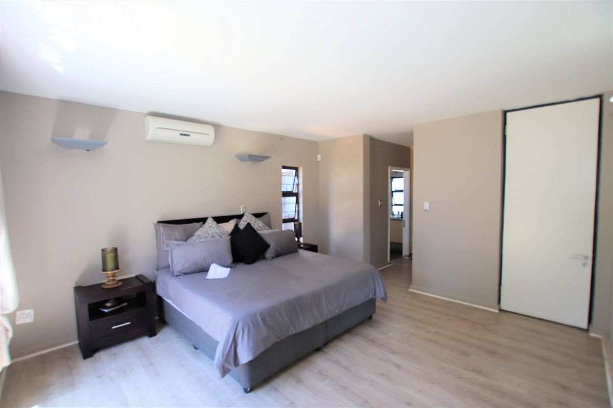 Spacious bedroom featuring laminate flooring, an air conditioning unit, and built-in storage, offering a comfortable and functional living space.
