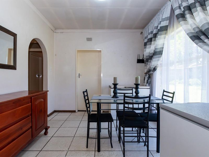 A dining area featuring tiled flooring, an arched doorway, and a large window allowing natural light into the space.