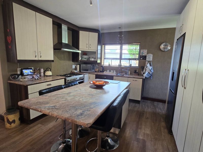 A functional kitchen featuring laminate cabinetry, stone-look countertops, a central island, and stainless steel appliances, offering a practical layout for daily cooking.