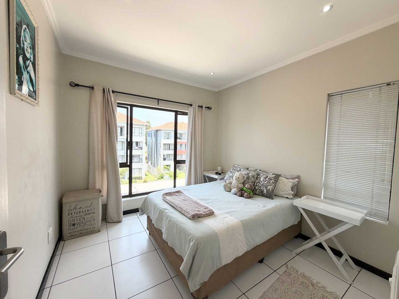 A bright and well-maintained bedroom featuring tiled flooring, recessed lighting, and a sliding glass door providing access to an outdoor area.