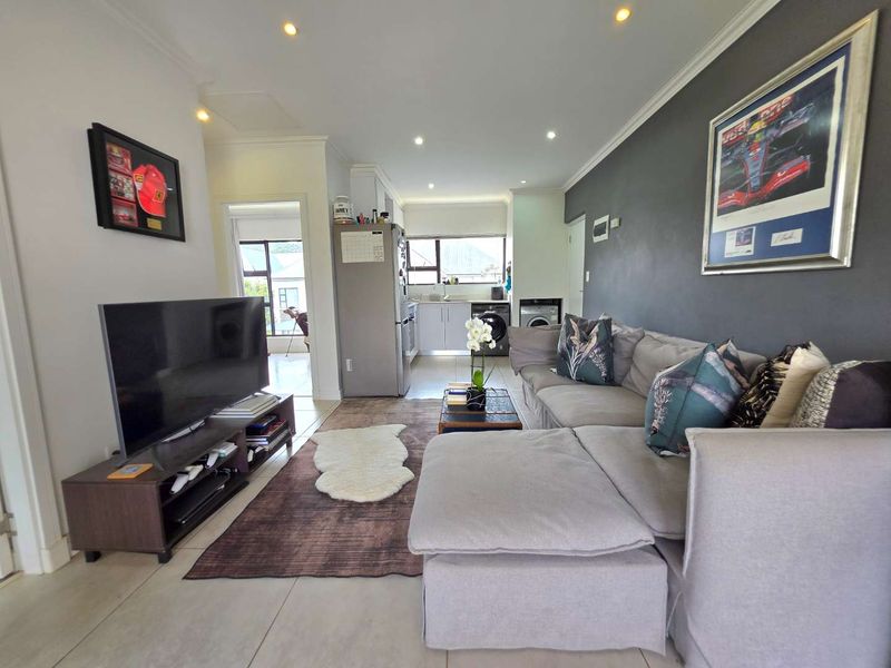 Open-plan living area featuring tiled floors, recessed lighting, and a functional kitchen space with integrated laundry facilities.