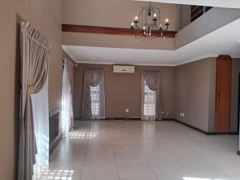 Spacious, light-filled living area featuring high ceilings, tiled flooring, a built-in fireplace, and a mezzanine level overlooking the main space.