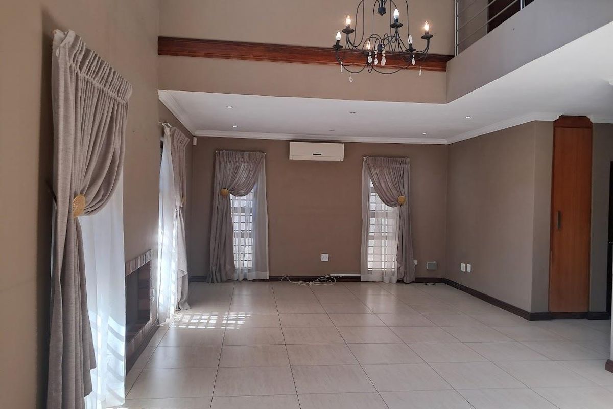 Spacious, light-filled living area featuring high ceilings, tiled flooring, a built-in fireplace, and a mezzanine level overlooking the main space.