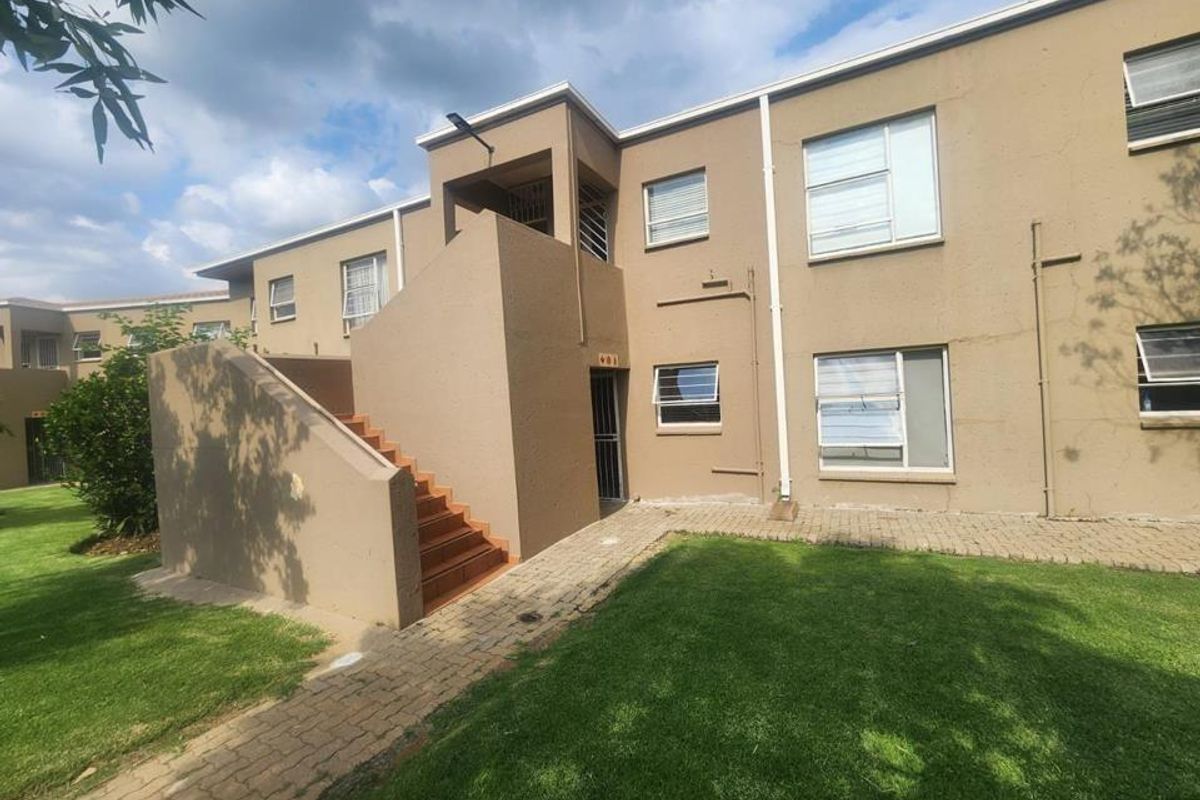 Exterior view of a townhouse complex featuring a concrete staircase, paved walkway, and landscaped lawn area.