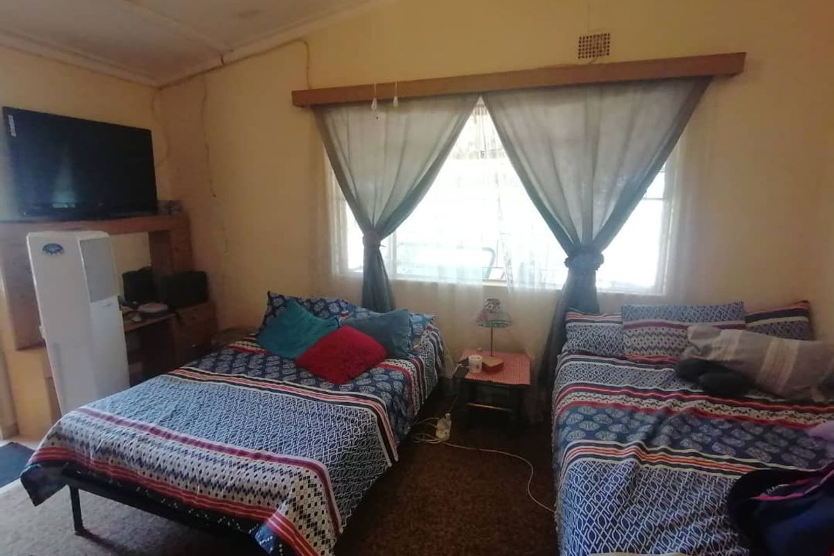 A bedroom featuring a large window with wooden trim, carpeted flooring, and a built-in shelving unit.