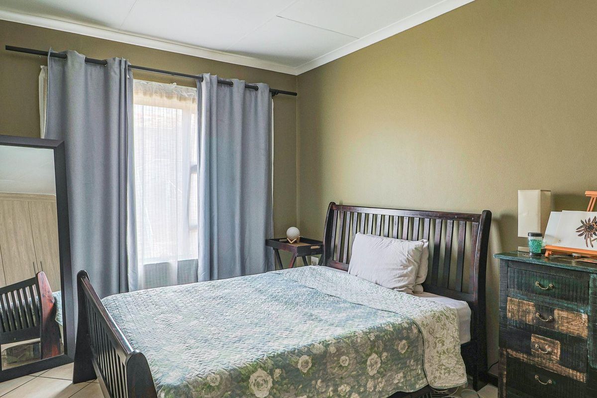 A bedroom featuring tiled flooring, neutral wall paint, and a window with curtain fixtures.