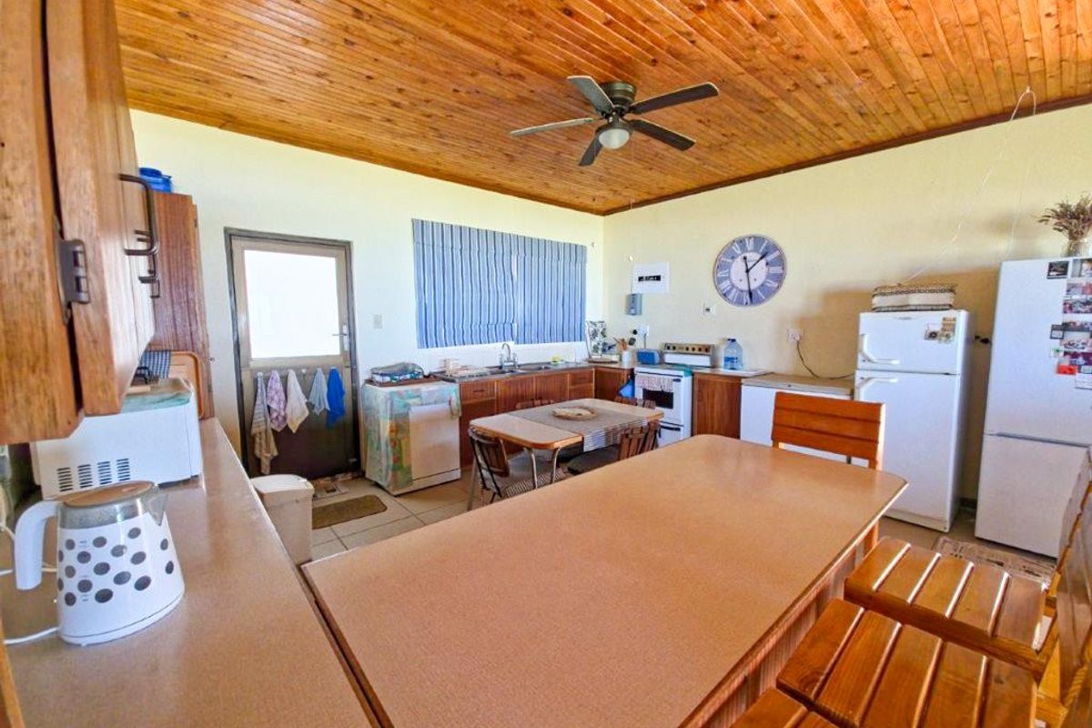 A functional kitchen featuring timber ceiling paneling, laminate countertops, and a breakfast bar area with direct access to the exterior.
