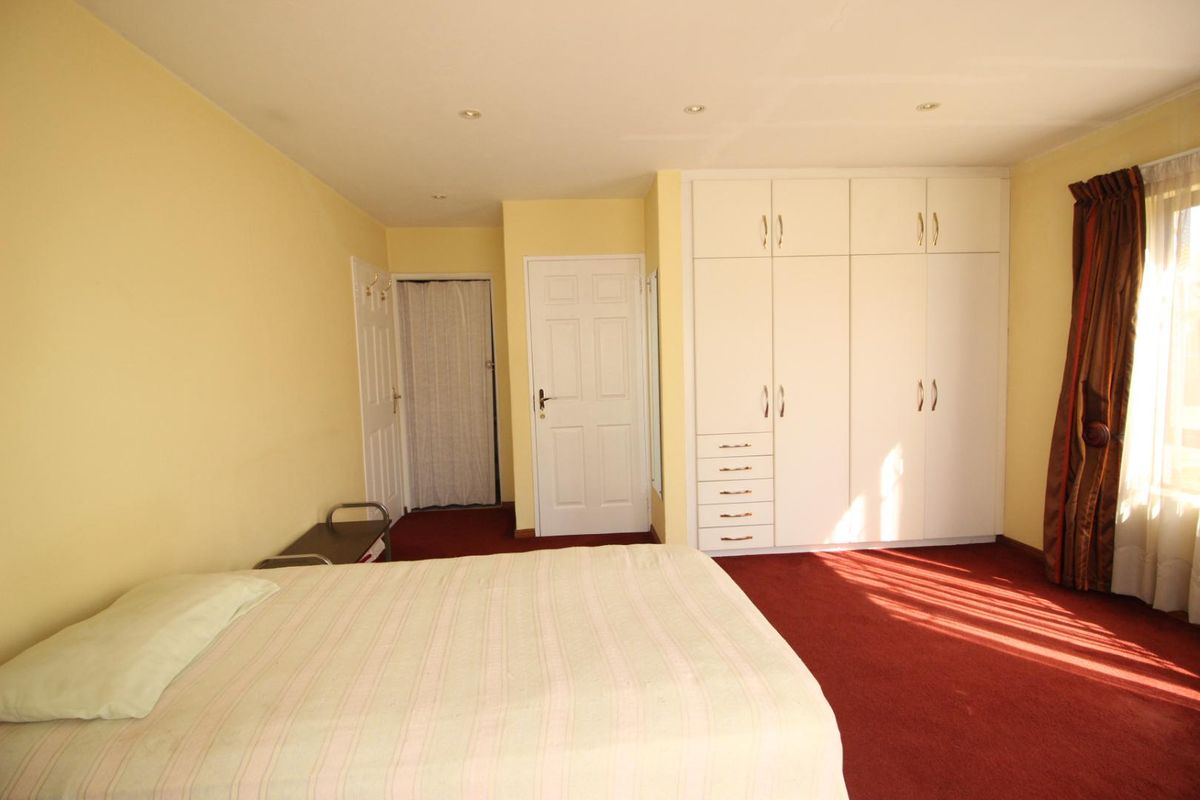 A spacious bedroom featuring built-in white cabinetry, recessed ceiling lighting, and carpeted flooring.