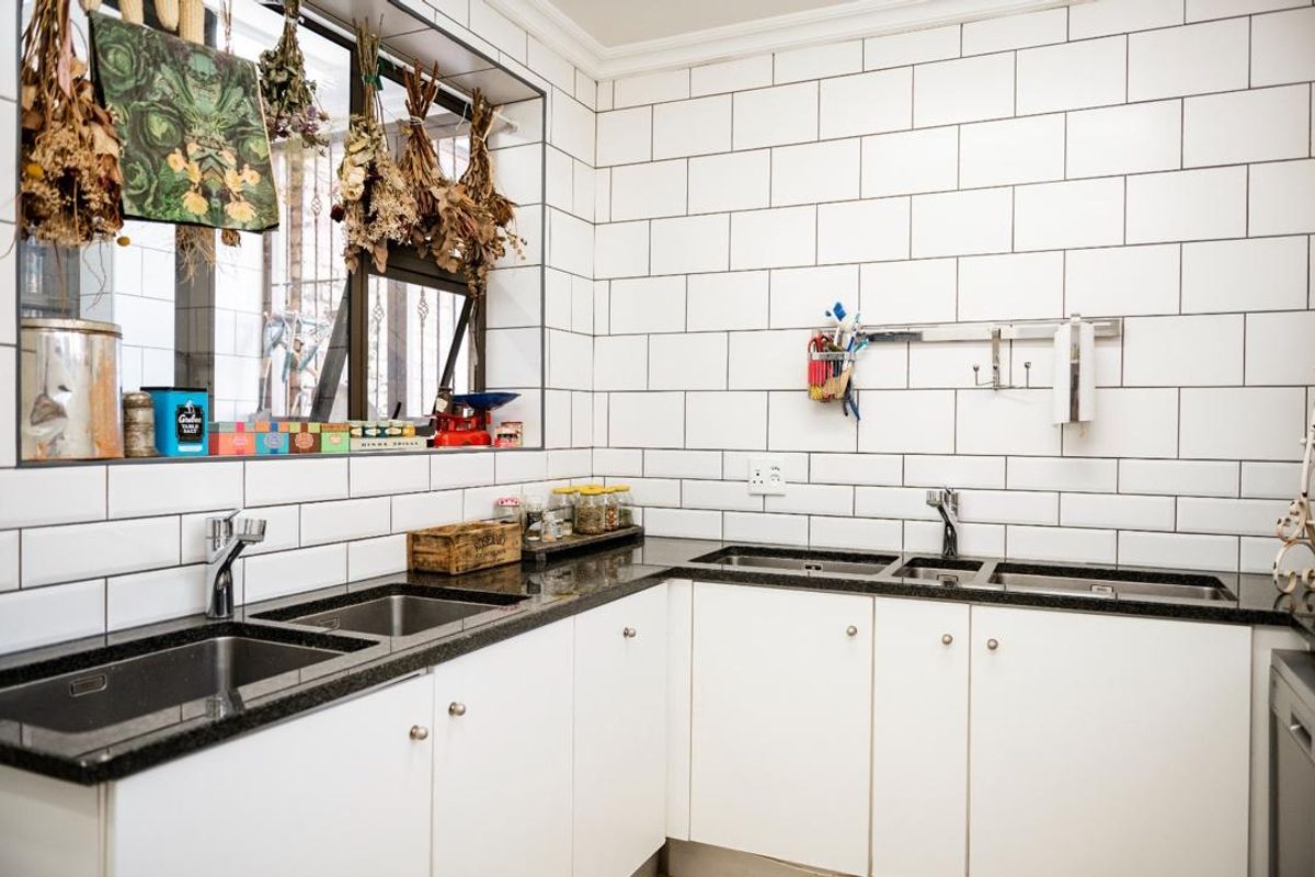 A functional kitchen area featuring white cabinetry, dark granite countertops, and a classic white subway tile backsplash with a double sink setup.