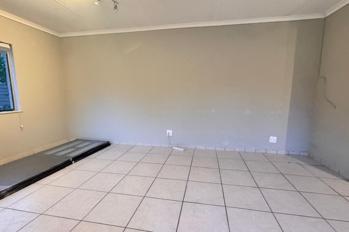 An empty living room featuring tiled flooring, neutral wall paint, and a window, providing a blank canvas for potential interior design updates.