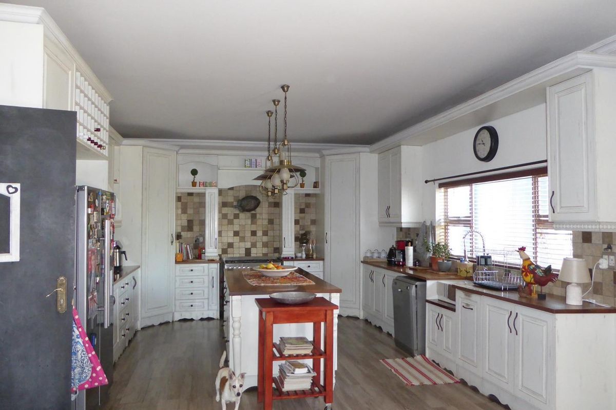 Spacious kitchen featuring white cabinetry, wooden countertops, a central island, tiled backsplash, and pendant lighting, offering a classic and functional cooking space.